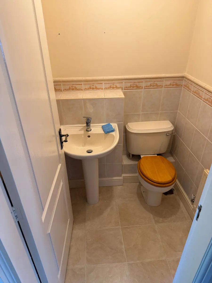 Cloakroom before the refit, with a pedestal basin, old toilet and dated beige tiles