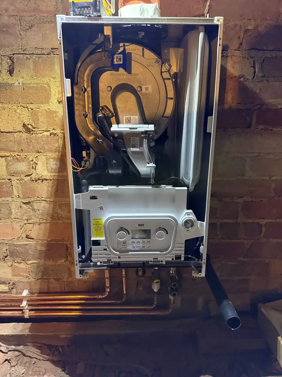 Baxi 800 boiler with the case off on a brick wall during installation, with new copper pipework below