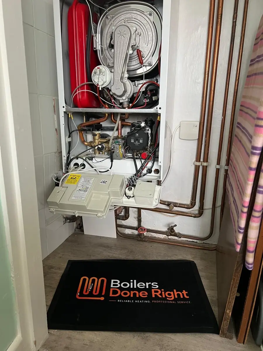 Boiler with the case open in a cupboard, Boilers Done Right mat on the floor