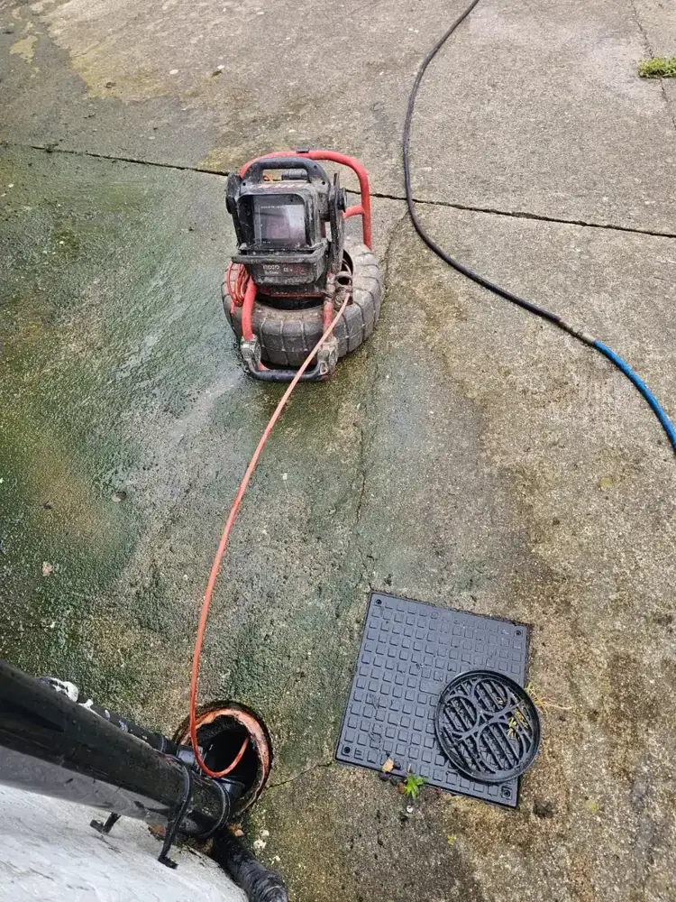 CCTV drain survey camera reel set up beside an open drain cover