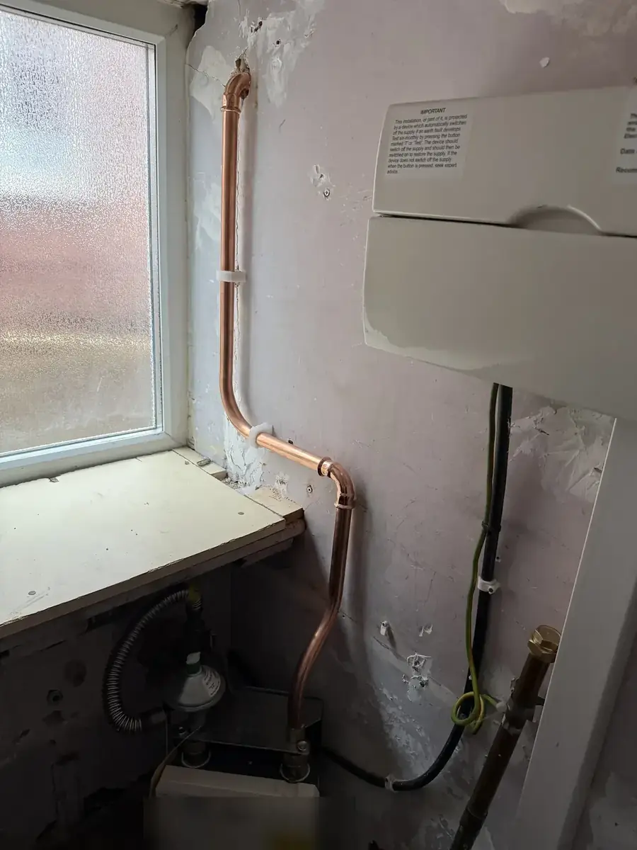 New copper gas pipework neatly clipped to a wall beside a window