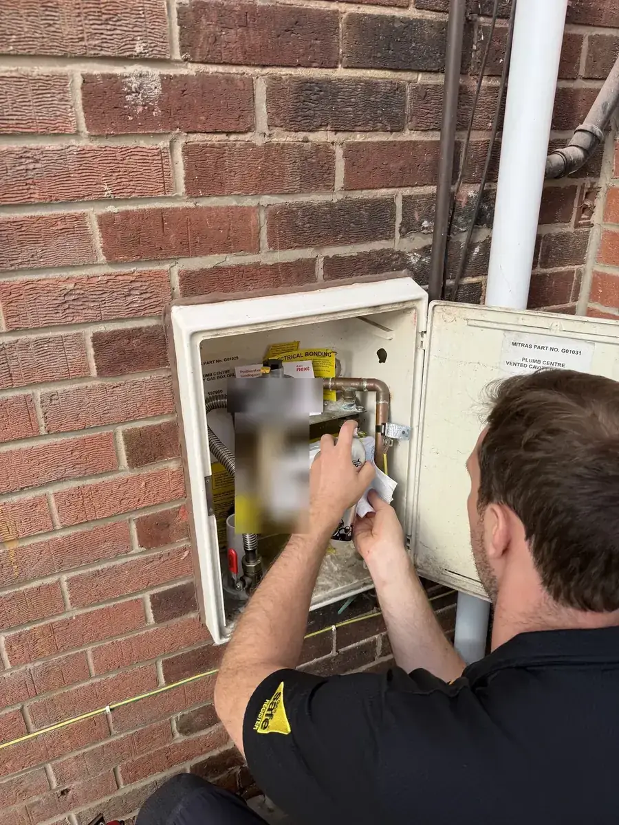 Engineer working at an external gas meter box on a brick wall