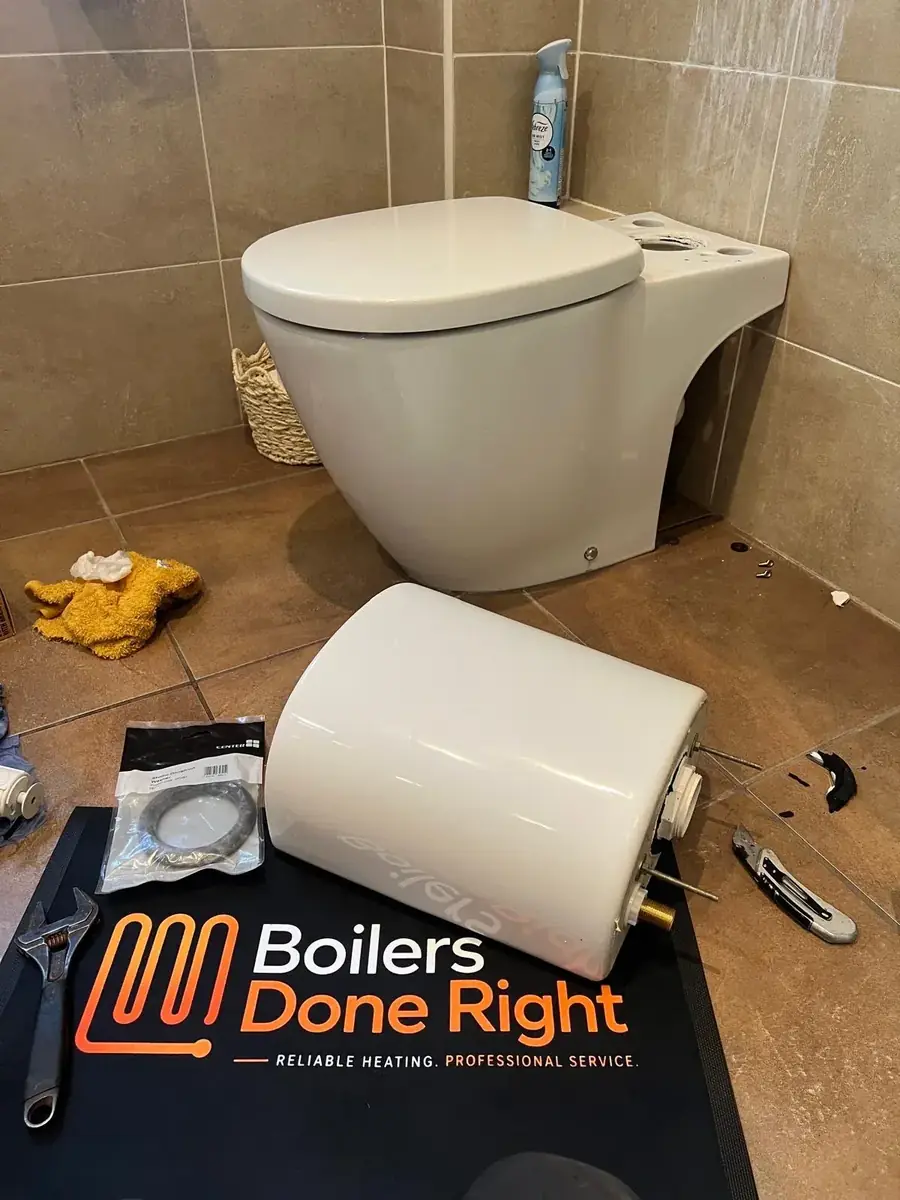 Toilet repair in a tiled bathroom with Boilers Done Right tools laid out on a branded mat